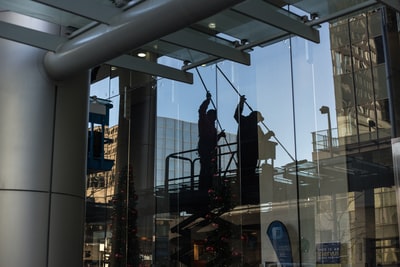 公用事业人员站在剪式平台上清洁玻璃窗